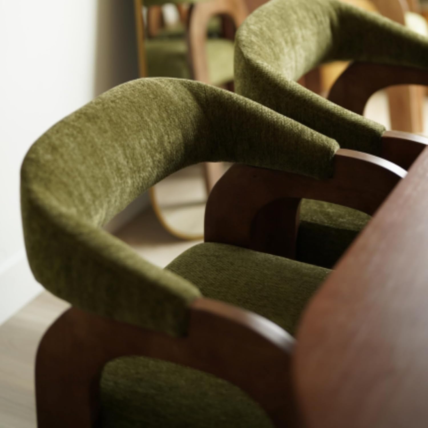 Close view of the curved chenille arms and wooden frame on a DAYALANE dining chair