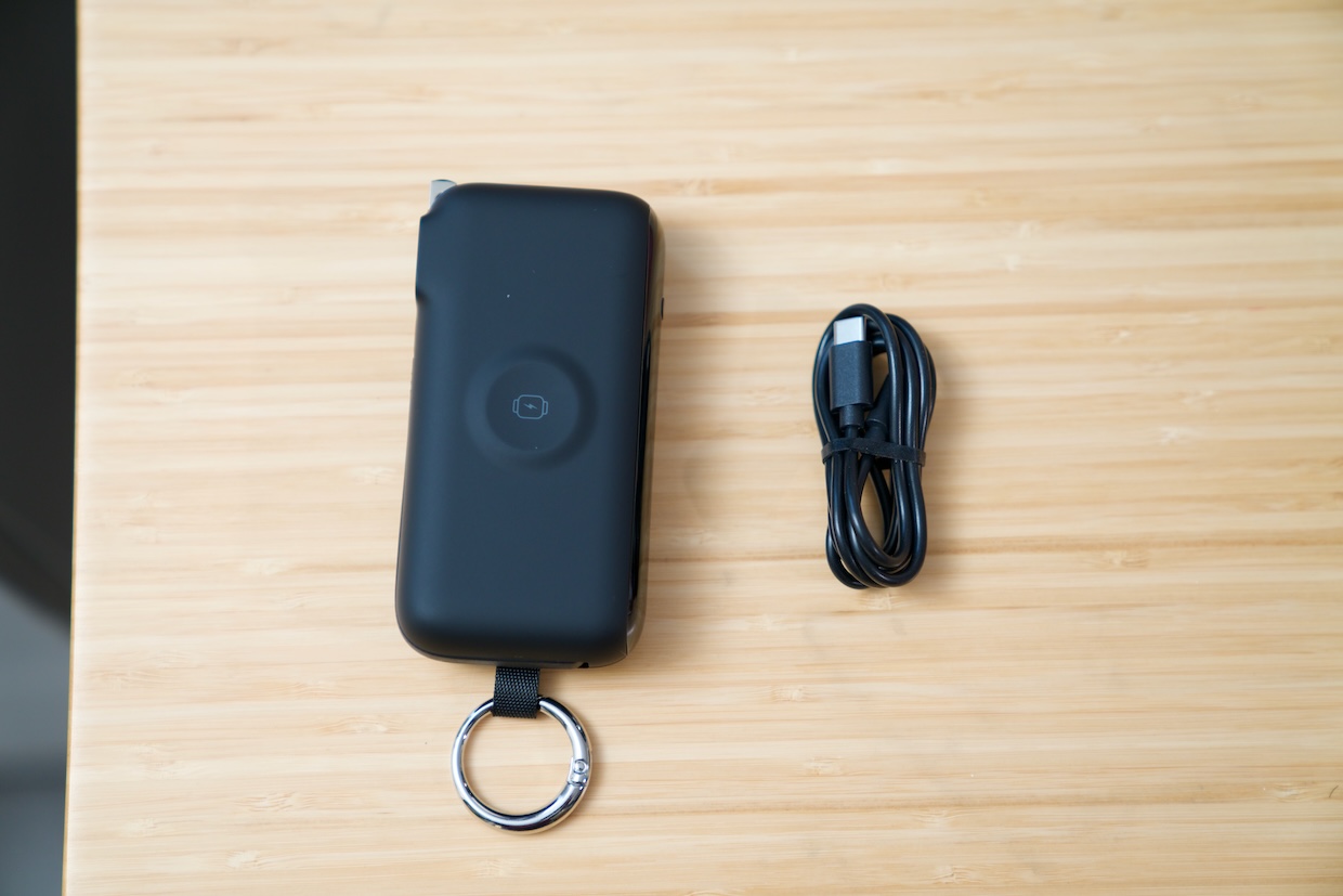 A hand holding the RORRY Flow power bank with its attached USB-C cable