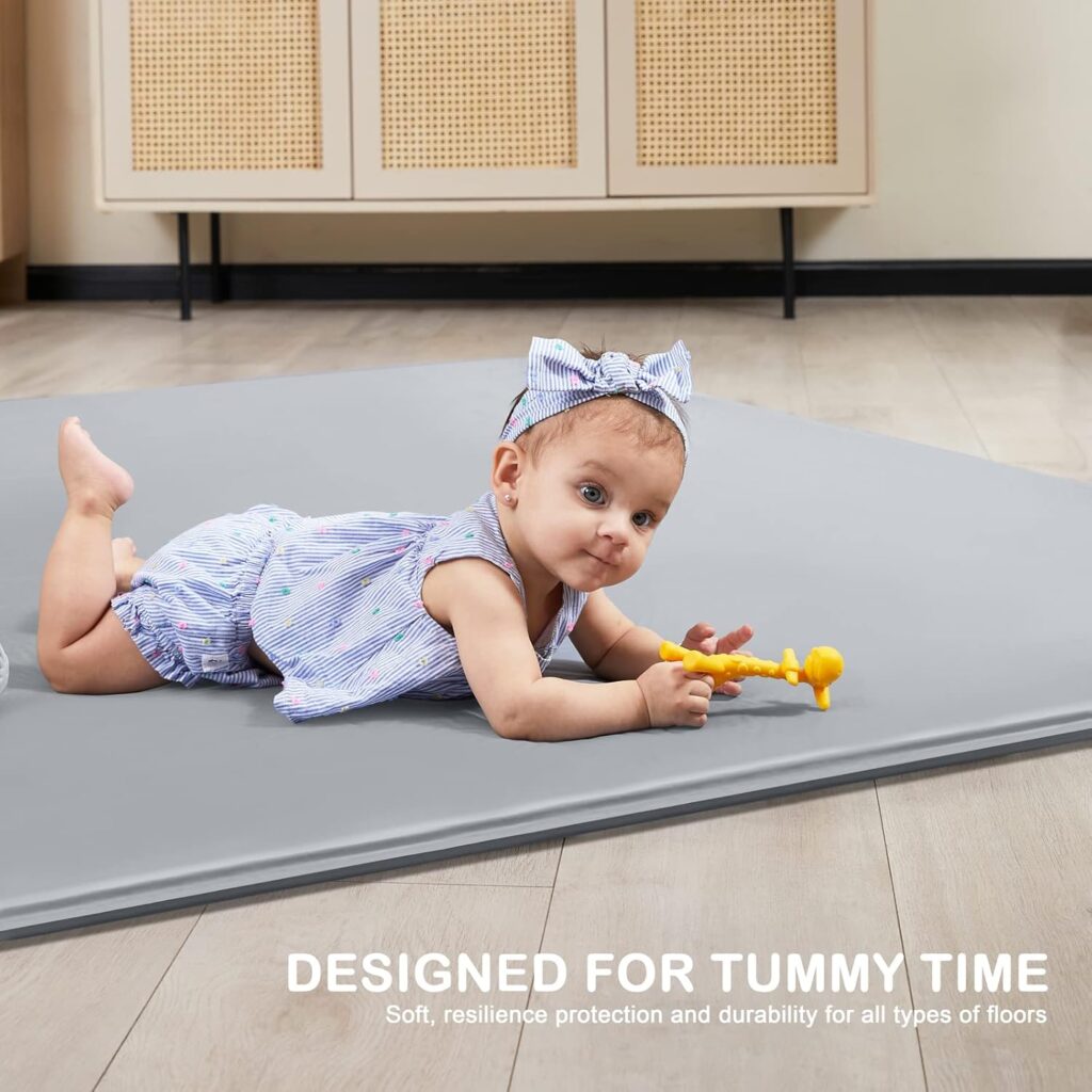 Baby lying on their tummy on the flat grey Angelbliss BG03 self-inflating mat with toys within reach