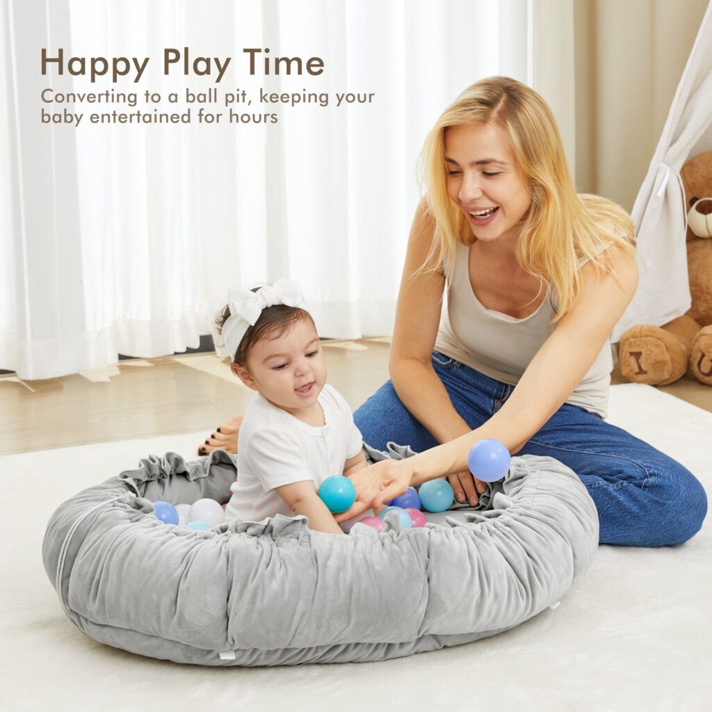 Parent sitting on the floor with a baby inside the Angelbliss play mat gathered into ball pit mode
