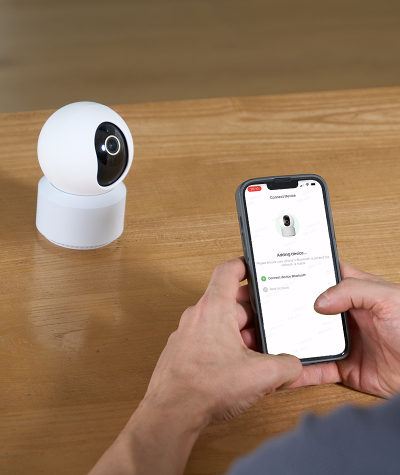 Hands pairing an Anona camera with a phone through the Anona Security app