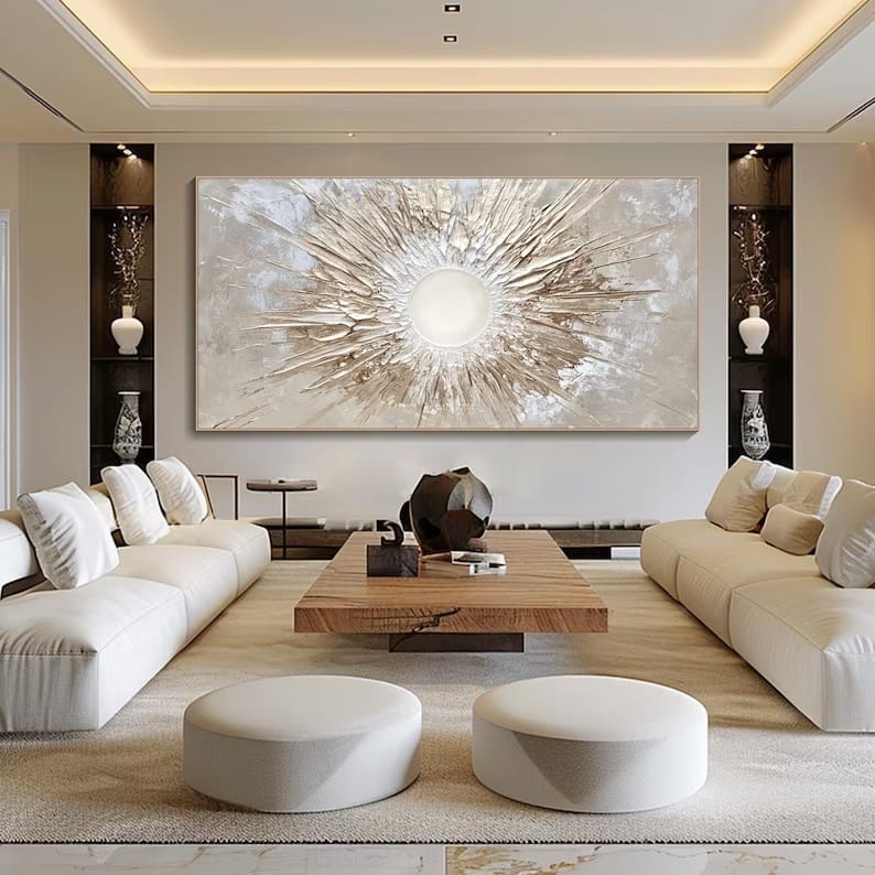 Cream and gold sunburst abstract painting with thick raised ridges, shown above a sofa in a large living room
