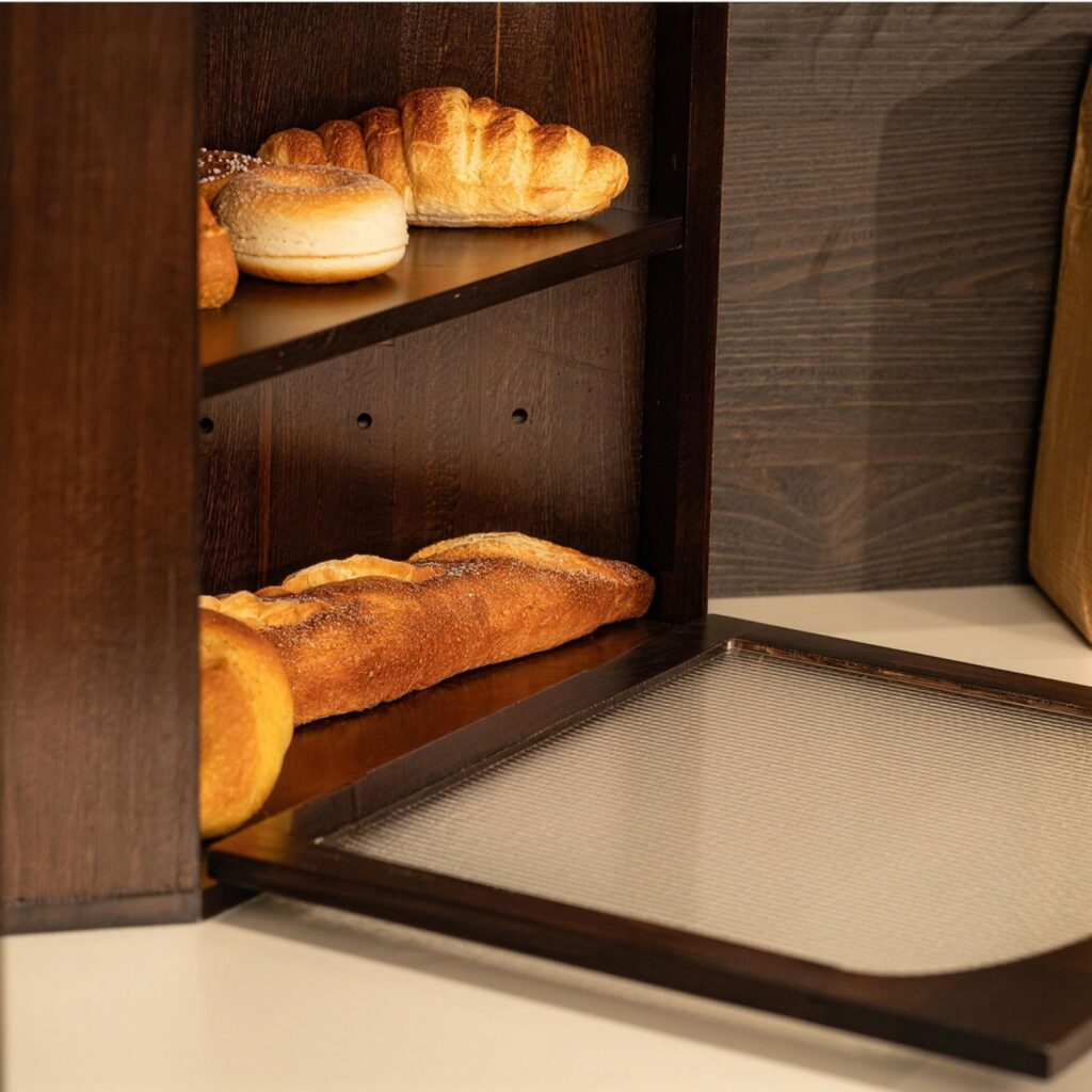 CheerNest solid pine bread box with its fluted acrylic door lowered, showing a baguette on the bottom level and rolls on the level above
