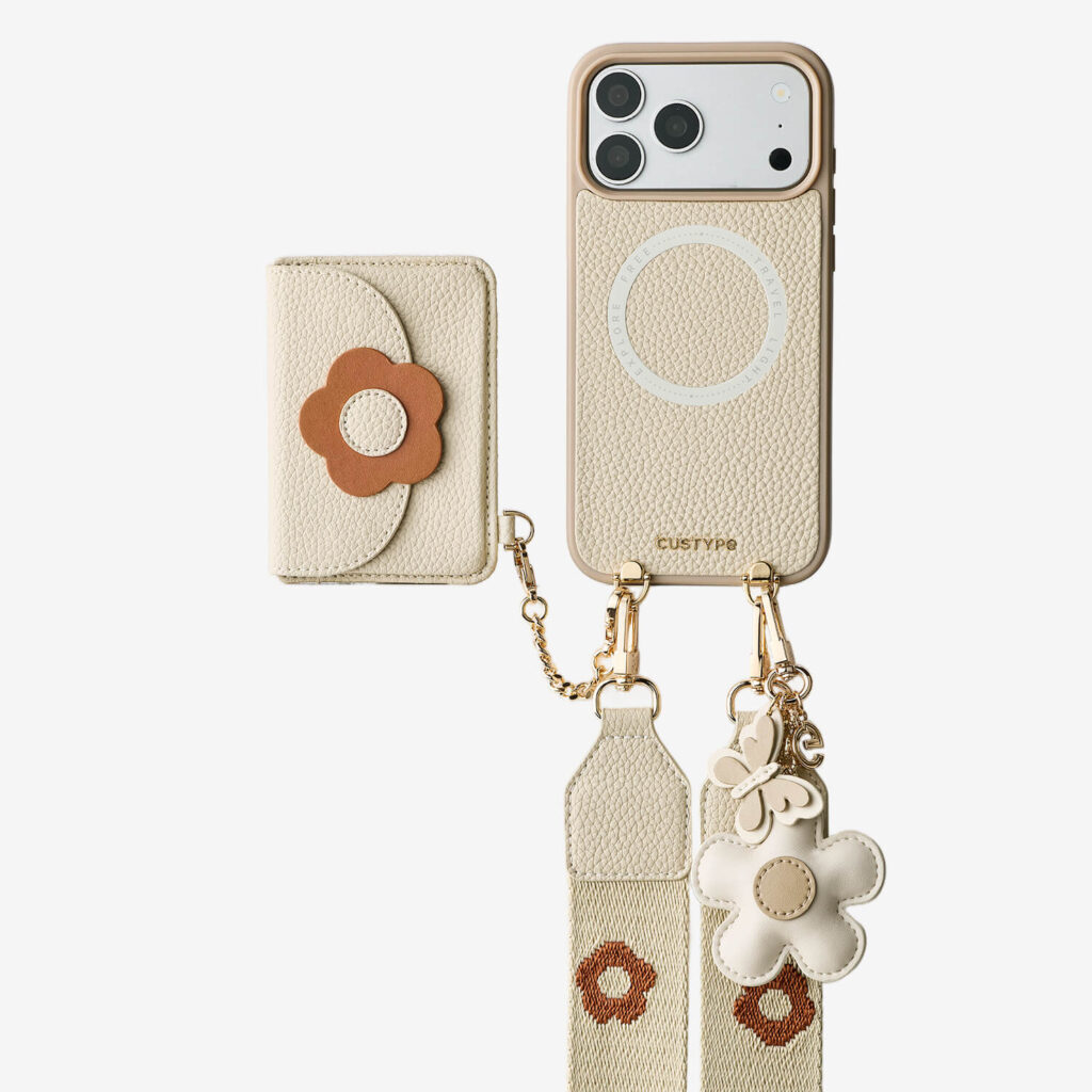 Cream Custype phone case with a magnetic ring, a detachable flower-motif card wallet, a charm and a woven strap