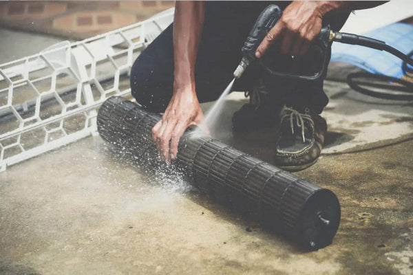 Hand rinsing a mini split blower wheel with a spray of water