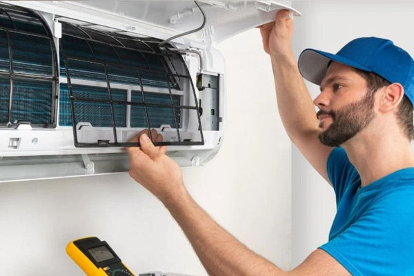 Technician lifting the front panel of a wall-mounted mini split to remove the air filter