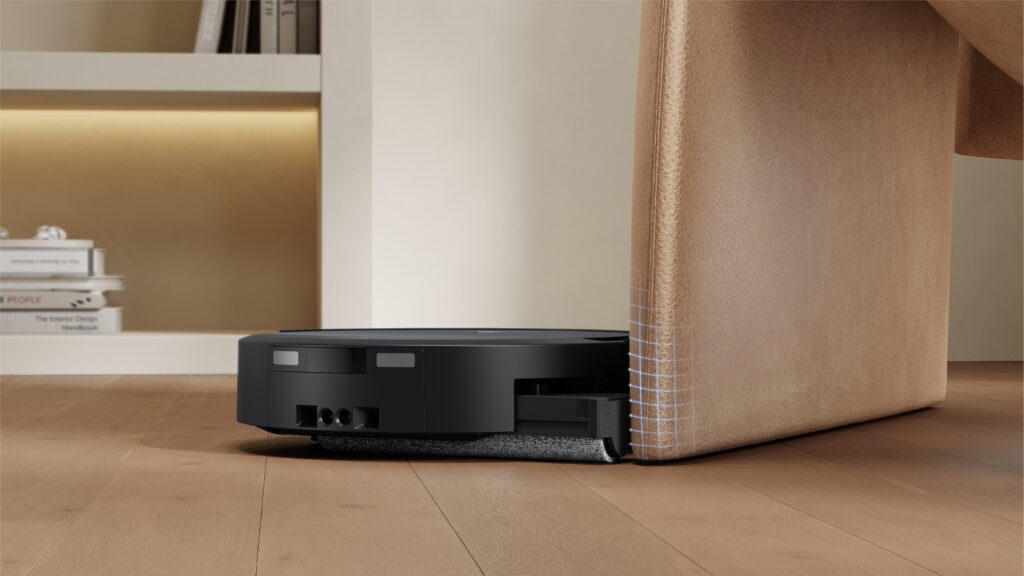 ECOVACS DEEBOT T90 PRO OMNI with its roller mop reaching the edge of a piece of furniture on a wood floor