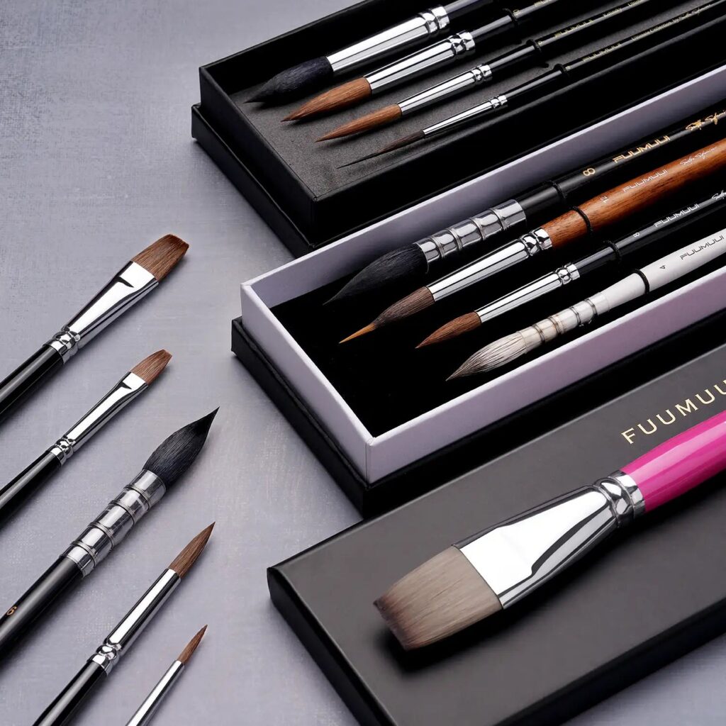 Fuumuui brushes in black presentation boxes beside loose flat and round brushes, including one with a pink handle