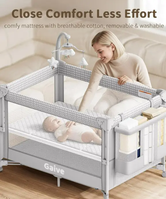 Gaive frame set up as a playard with grey mesh sides and a parent leaning in toward a baby lying on the mattress