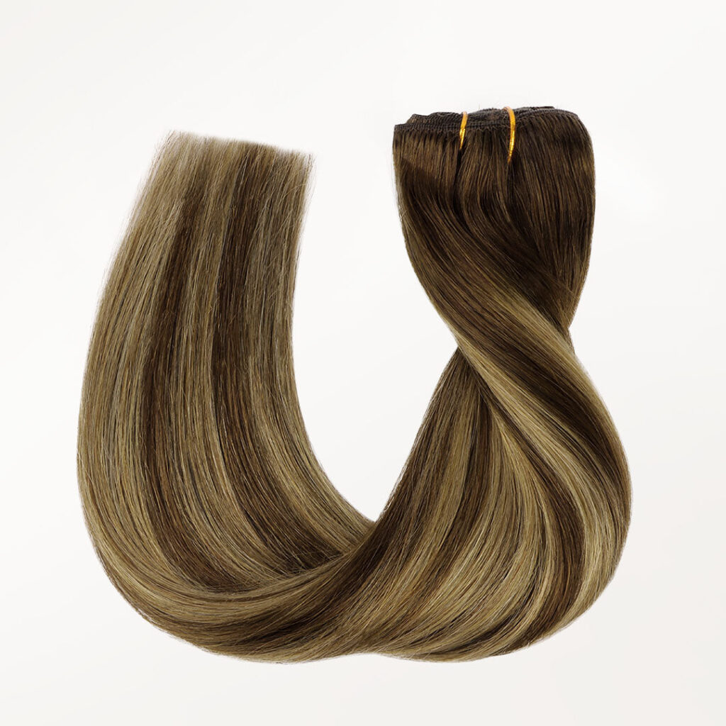 Caramel blonde balayage clip-in extensions twisted into a loop on a light background