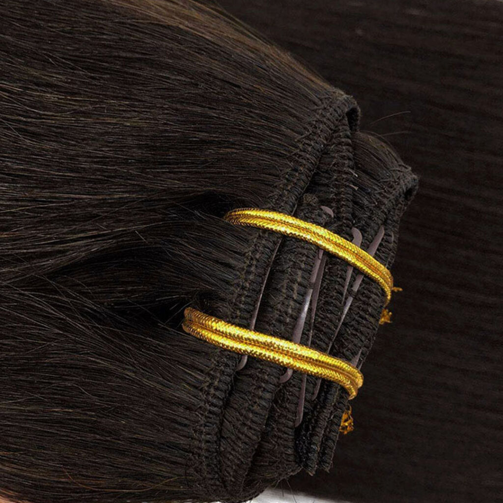 Close-up of a dark brown clip-in weft with gold-colored stitching at the top edge
