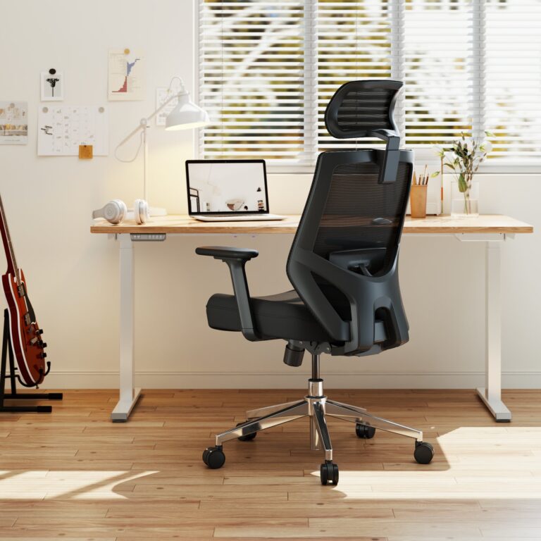 Black mesh ergonomic office chair with a headrest at a wooden home office desk beside a sunny window