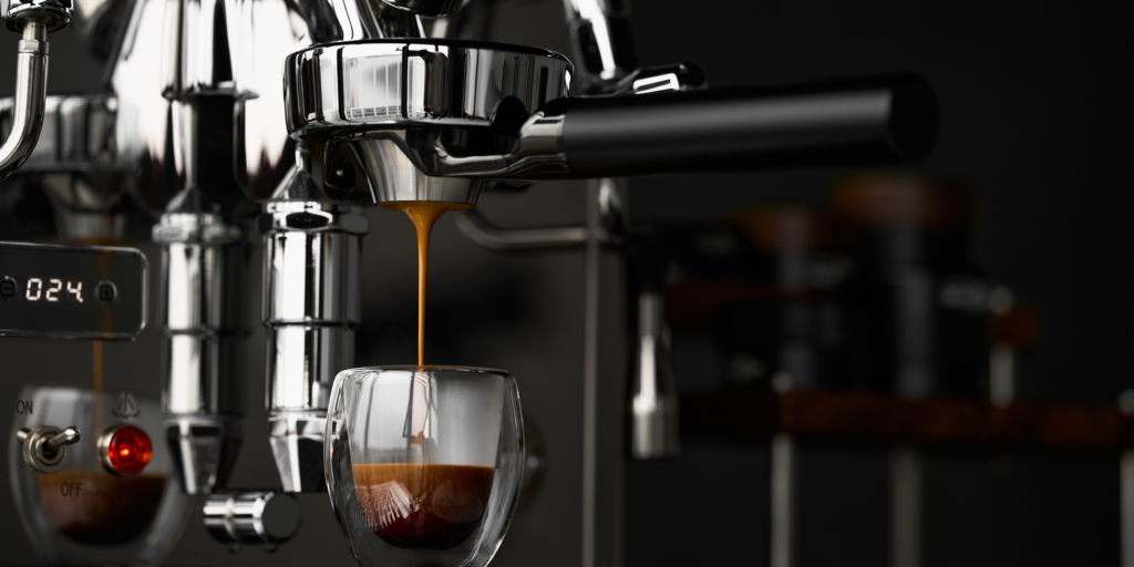 Espresso flowing from a portafilter into a double-walled glass cup