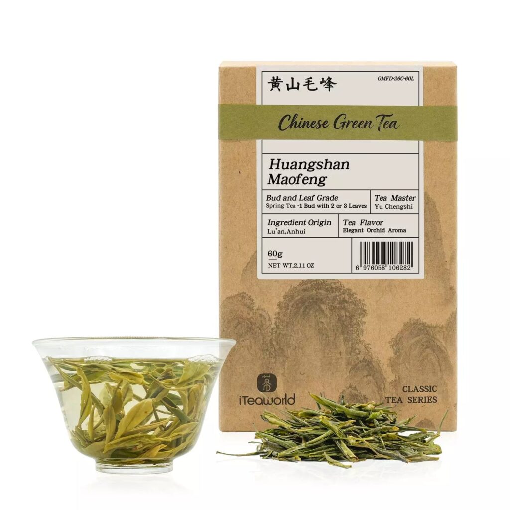iTeaworld Huangshan Maofeng green tea box beside a glass cup of brewed tea and dry leaves