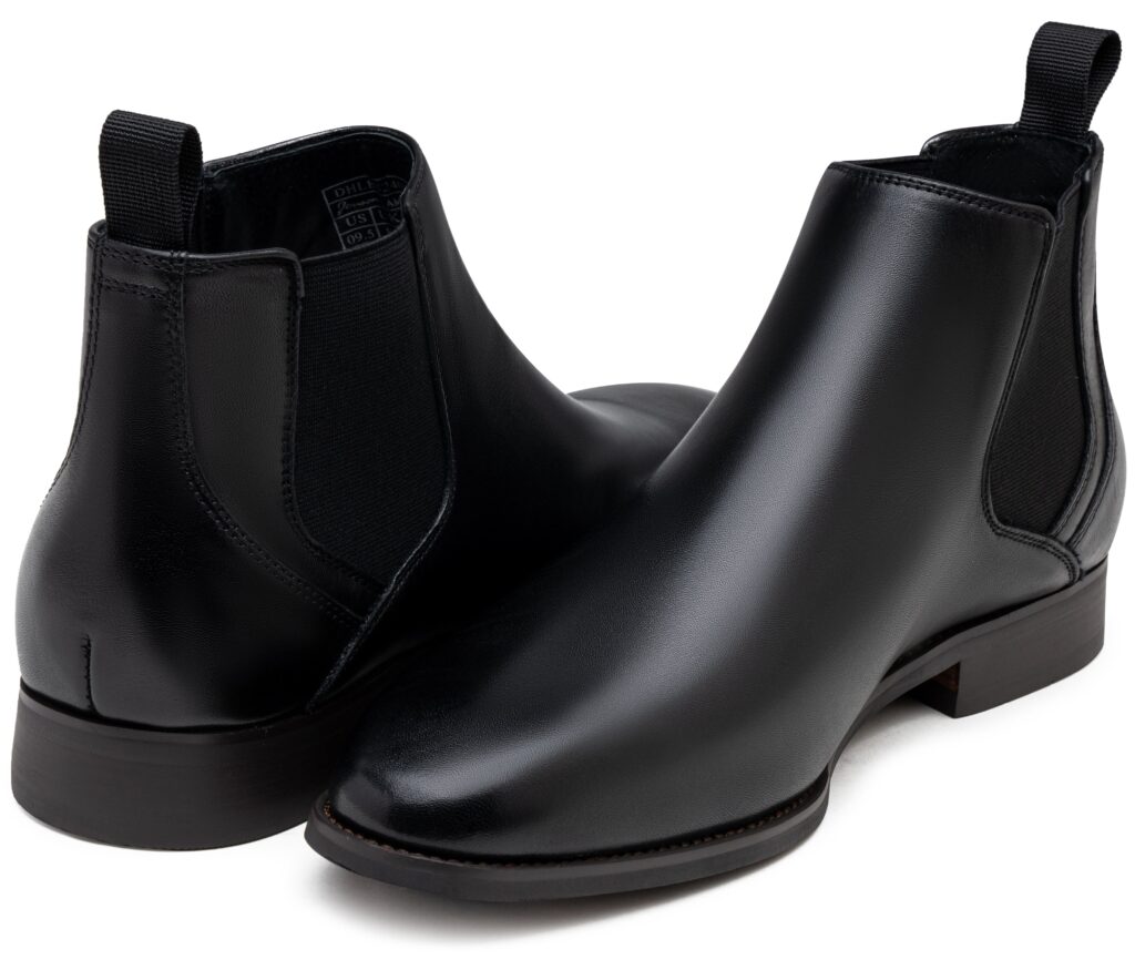 Pair of black leather Chelsea boots, one turned to show the back pull tab and elastic panel