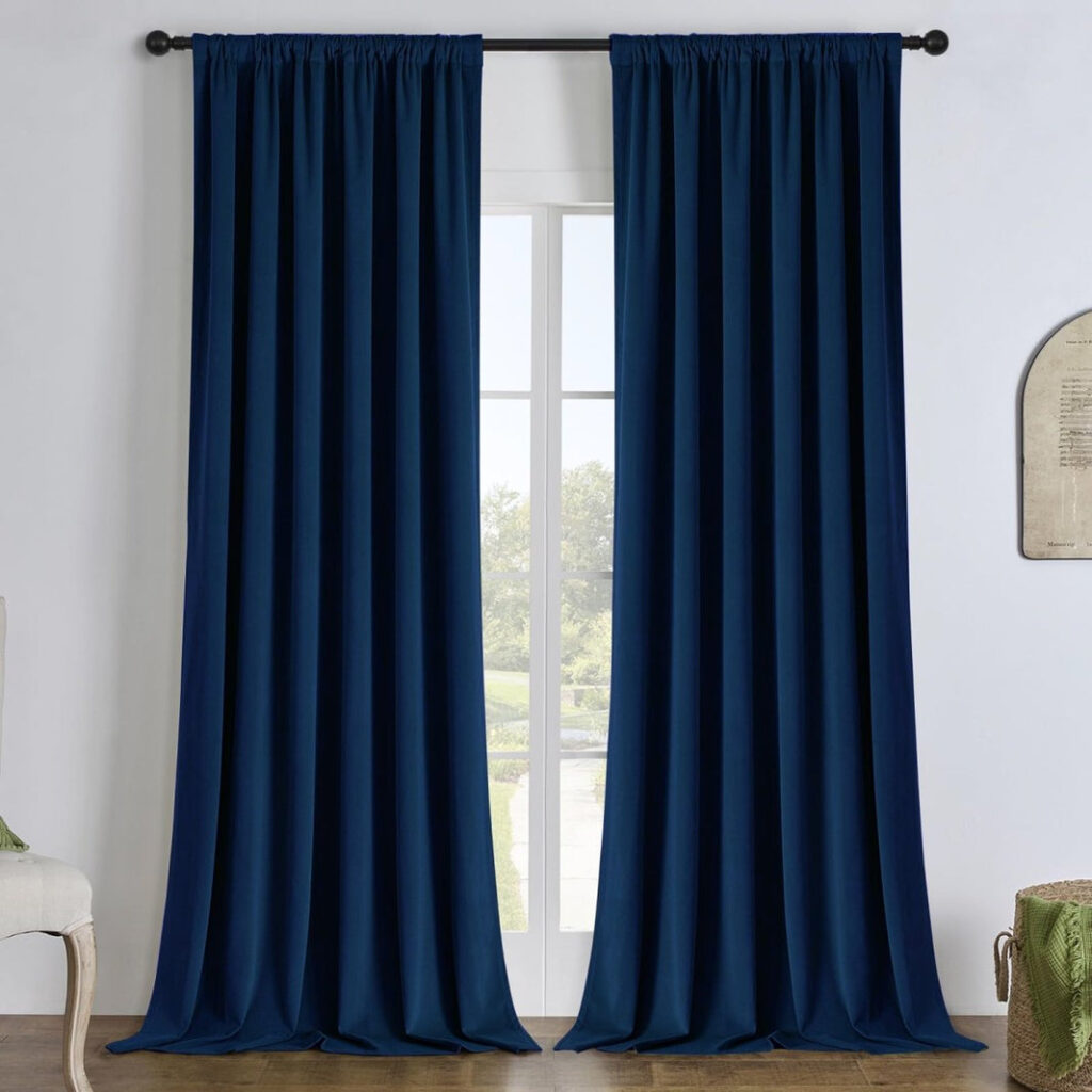 Deep blue Joydeco velvet curtains with a rod-pocket top hanging beside a tall window