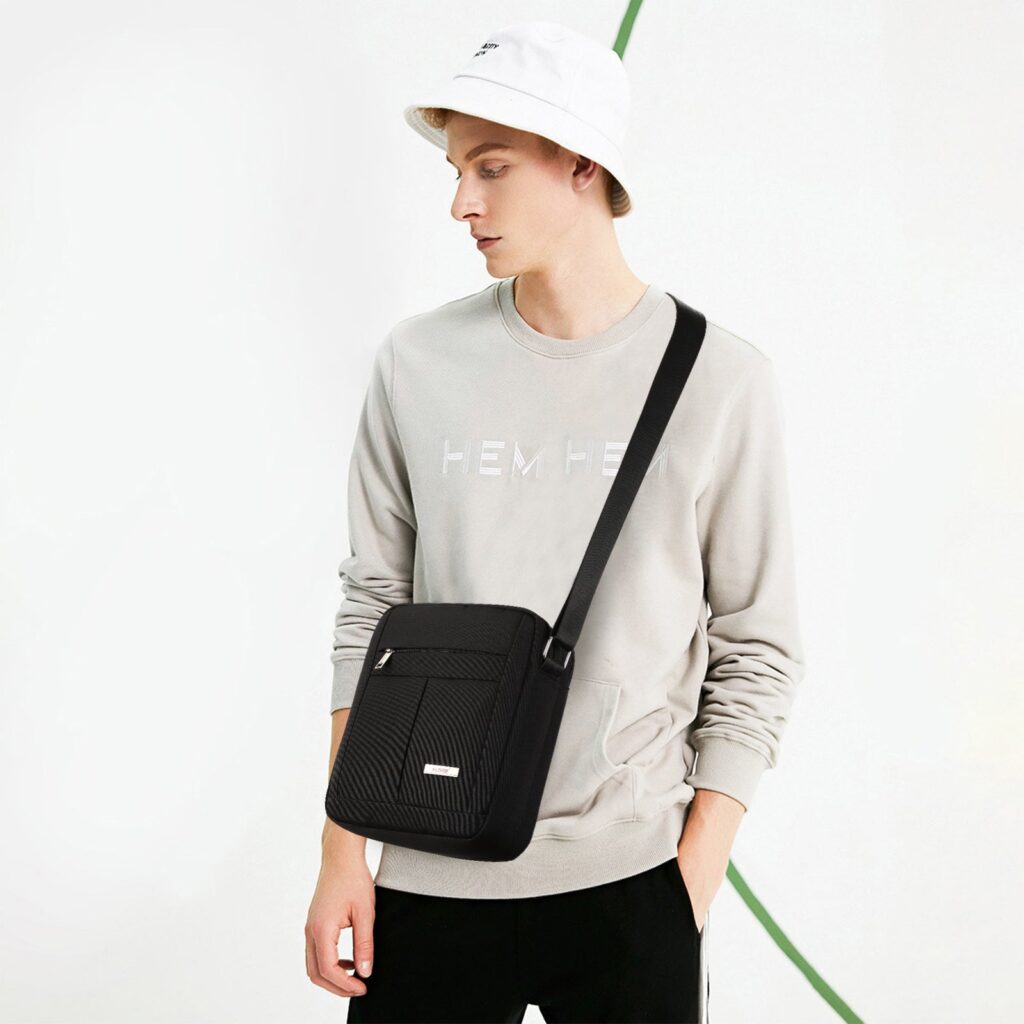 Man in a gray sweater wearing a small black nylon crossbody messenger bag