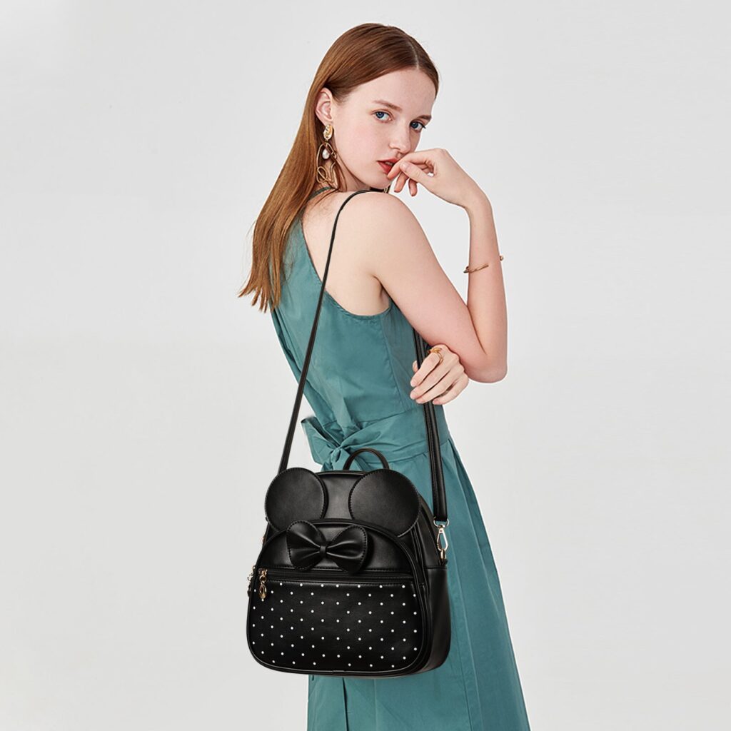 Model carrying the black polka-dot KL928 bowknot mini bag with round ears as a crossbody on one strap