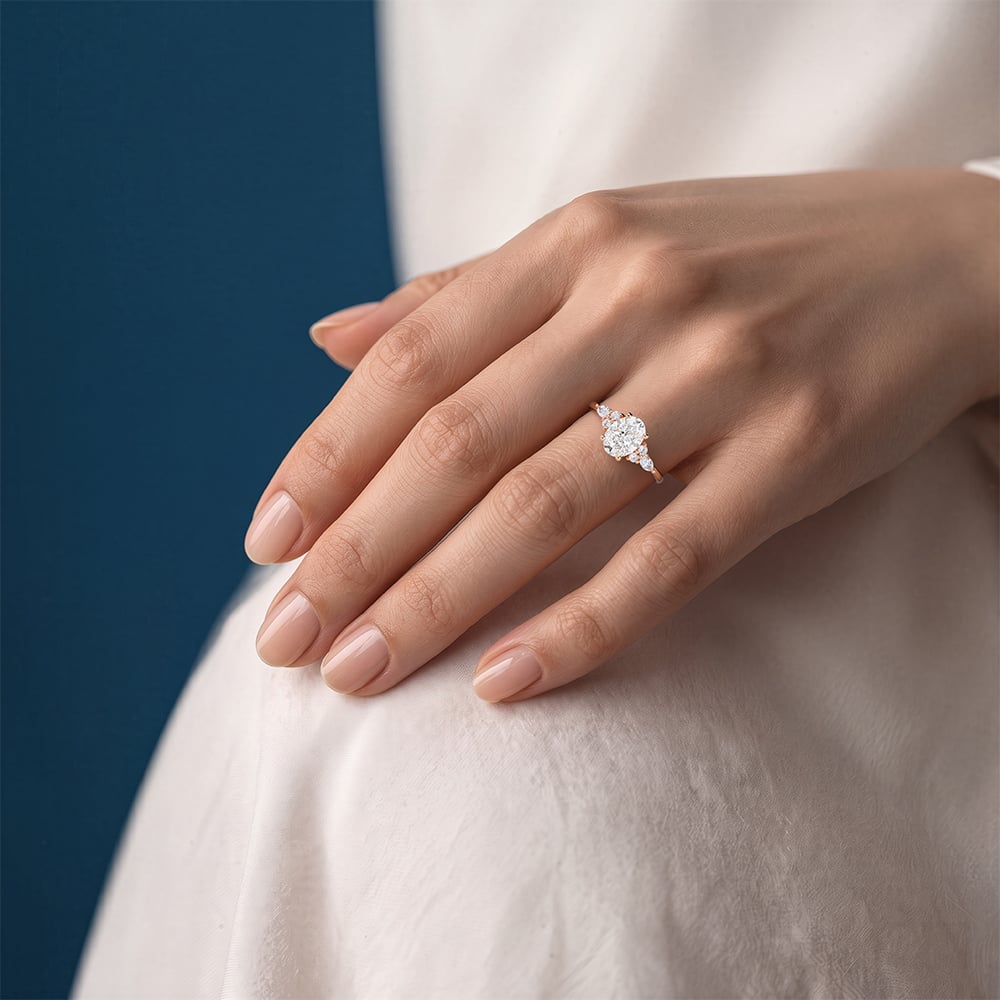 Oval lab-grown diamond ring in rose gold worn on a hand resting against a white sleeve