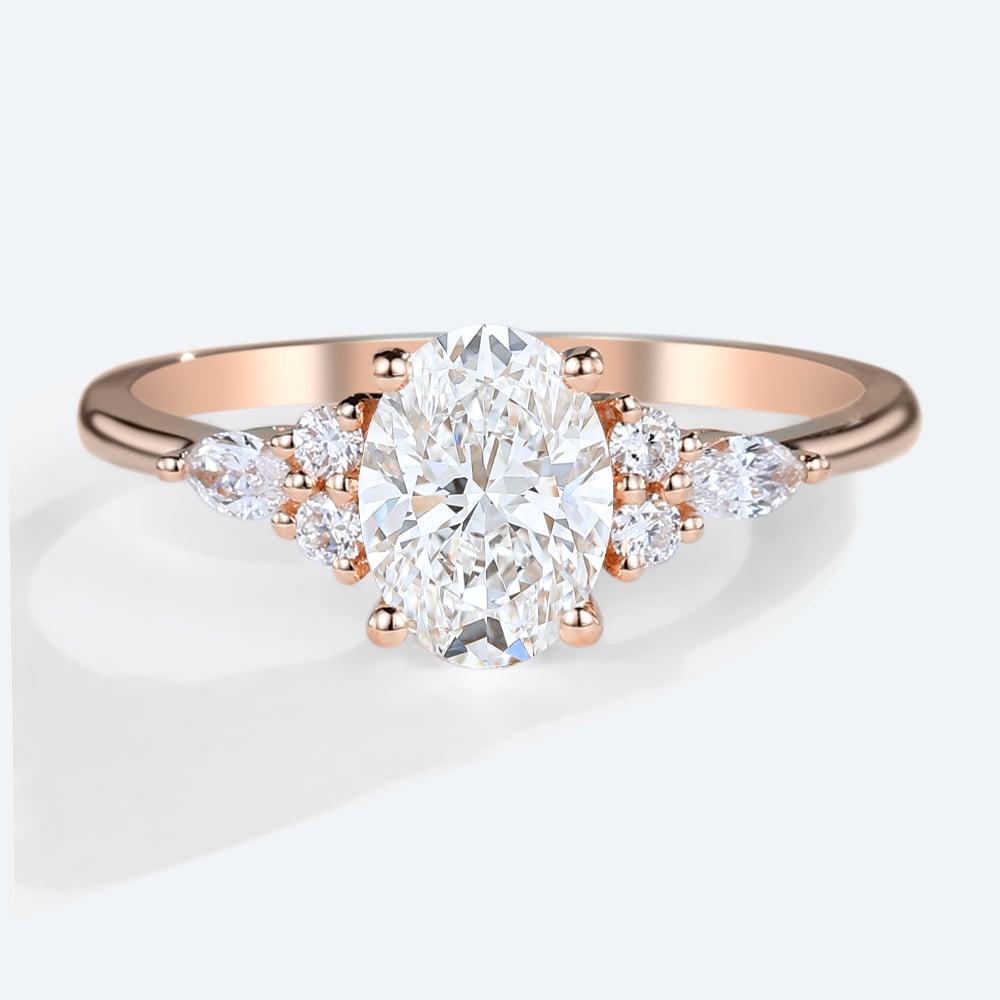 Close-up of an oval diamond ring in rose gold with small accent stones on either side