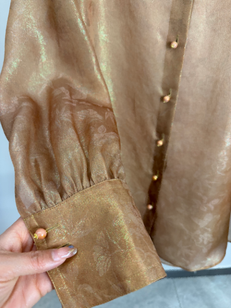 Close-up of the blouse cuff and button placket with the woven shimmer visible in the fabric