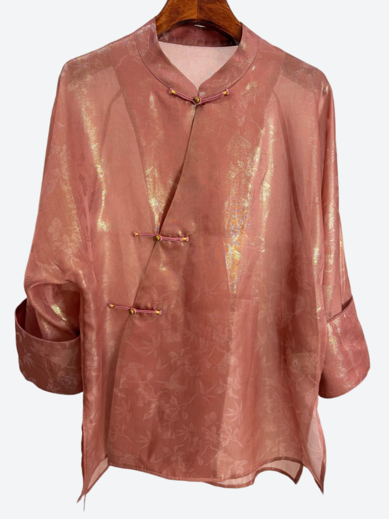 Pink shimmer brocade blouse with a frog-button front laid flat against a pale background