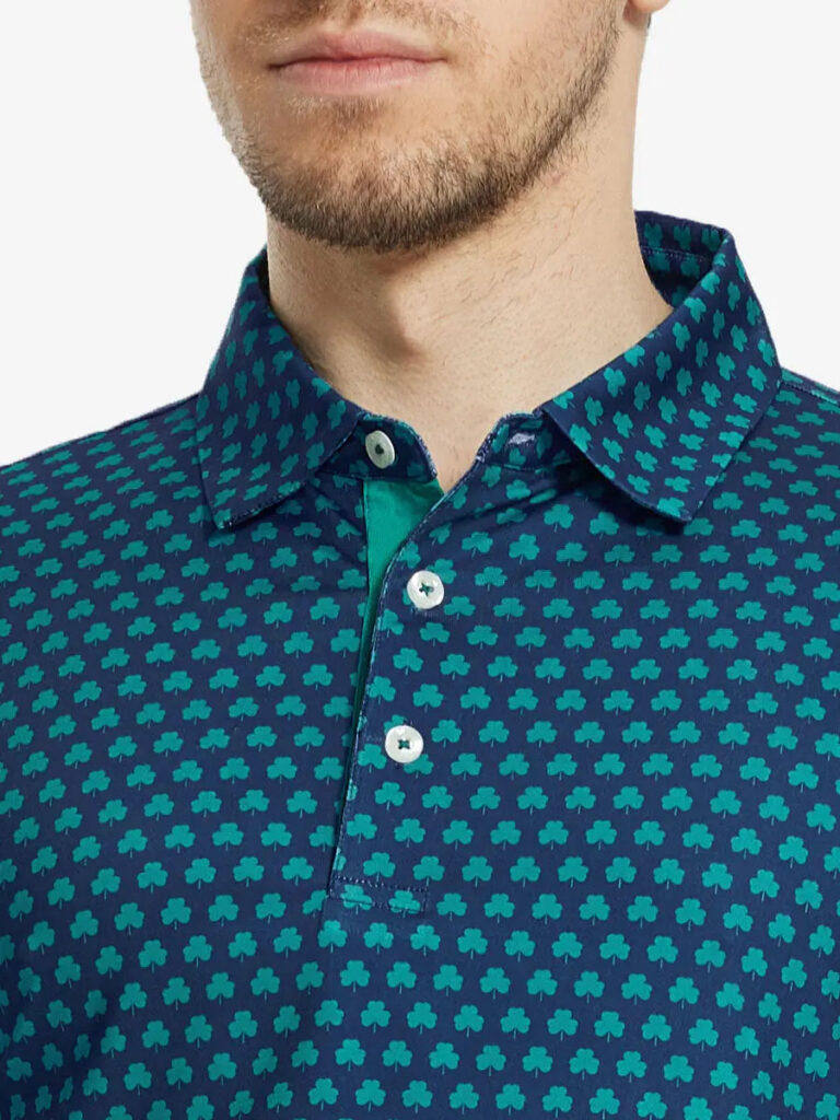 Close-up of the collar and buttons on a navy Maelreg print polo with a green shamrock pattern