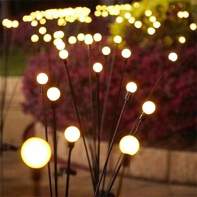 Masdio Eclipse firefly lights glowing on thin stakes above a flower bed
