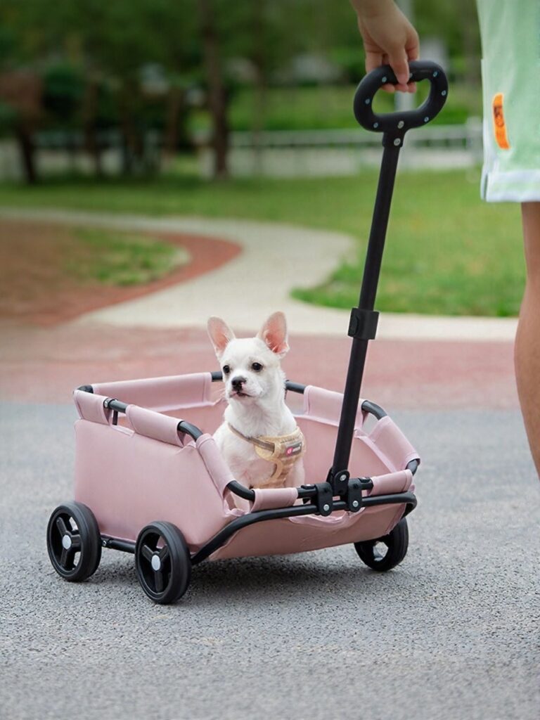 Pink folding pet stroller wagon with a small white dog sitting inside