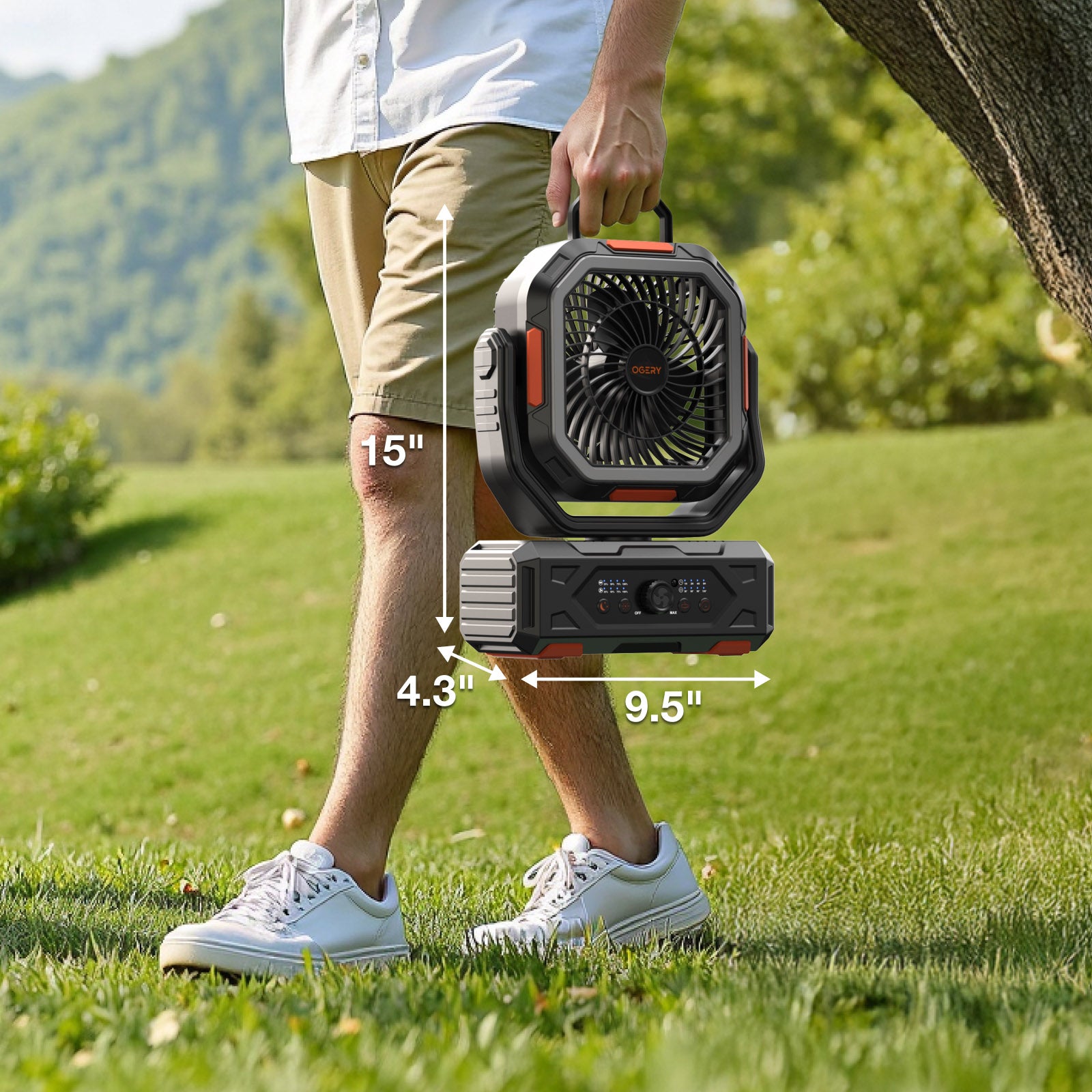 A person carrying the OGERY F11 camping fan by its top handle across a grassy hillside