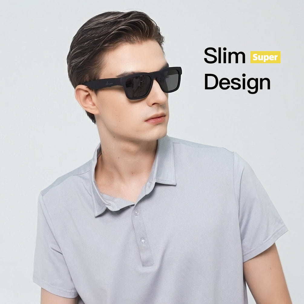 Man in a gray polo wearing slim black Bluetooth sunglasses against a plain light background