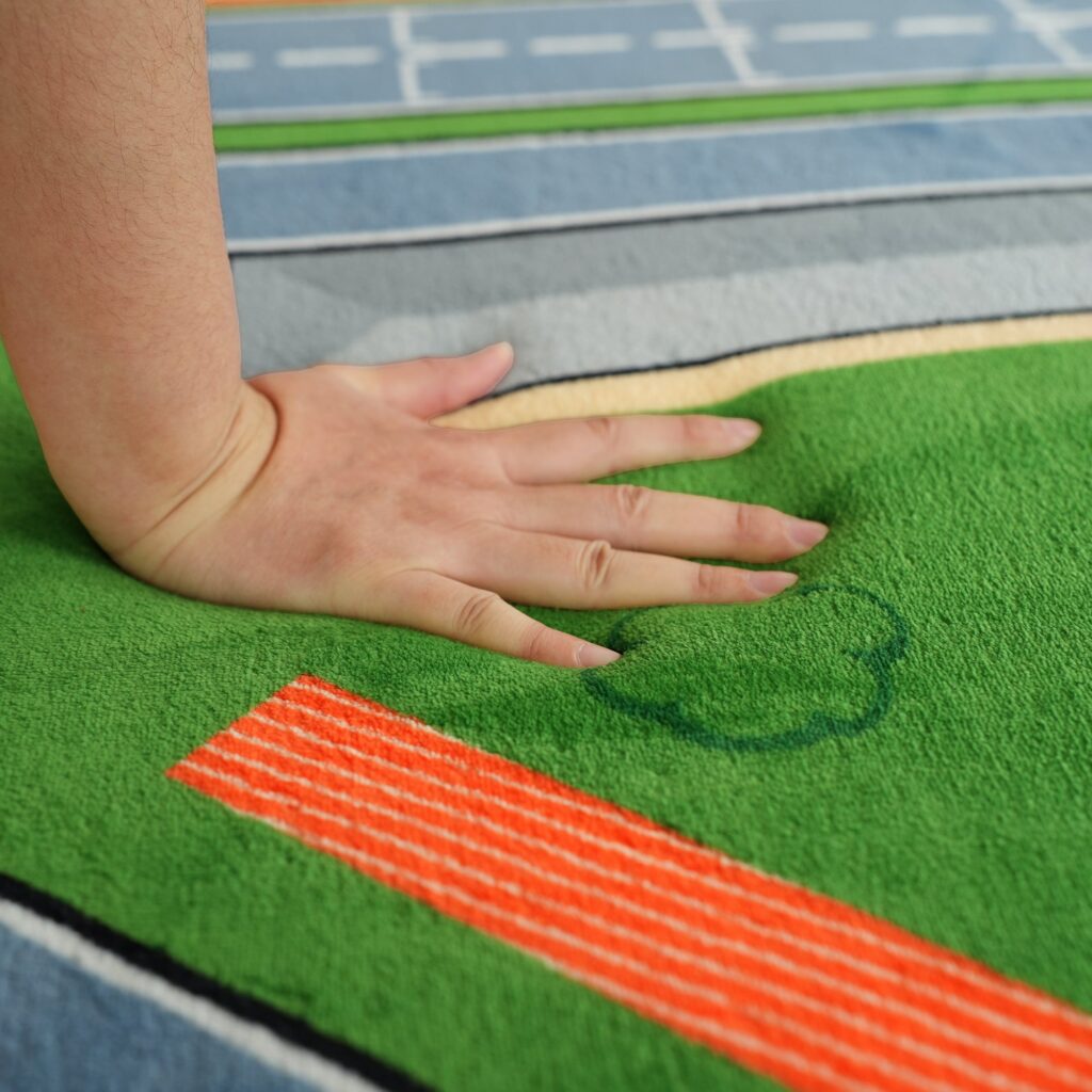 Hand pressing into the plush velvet surface of the PaPaMat Race Track mat