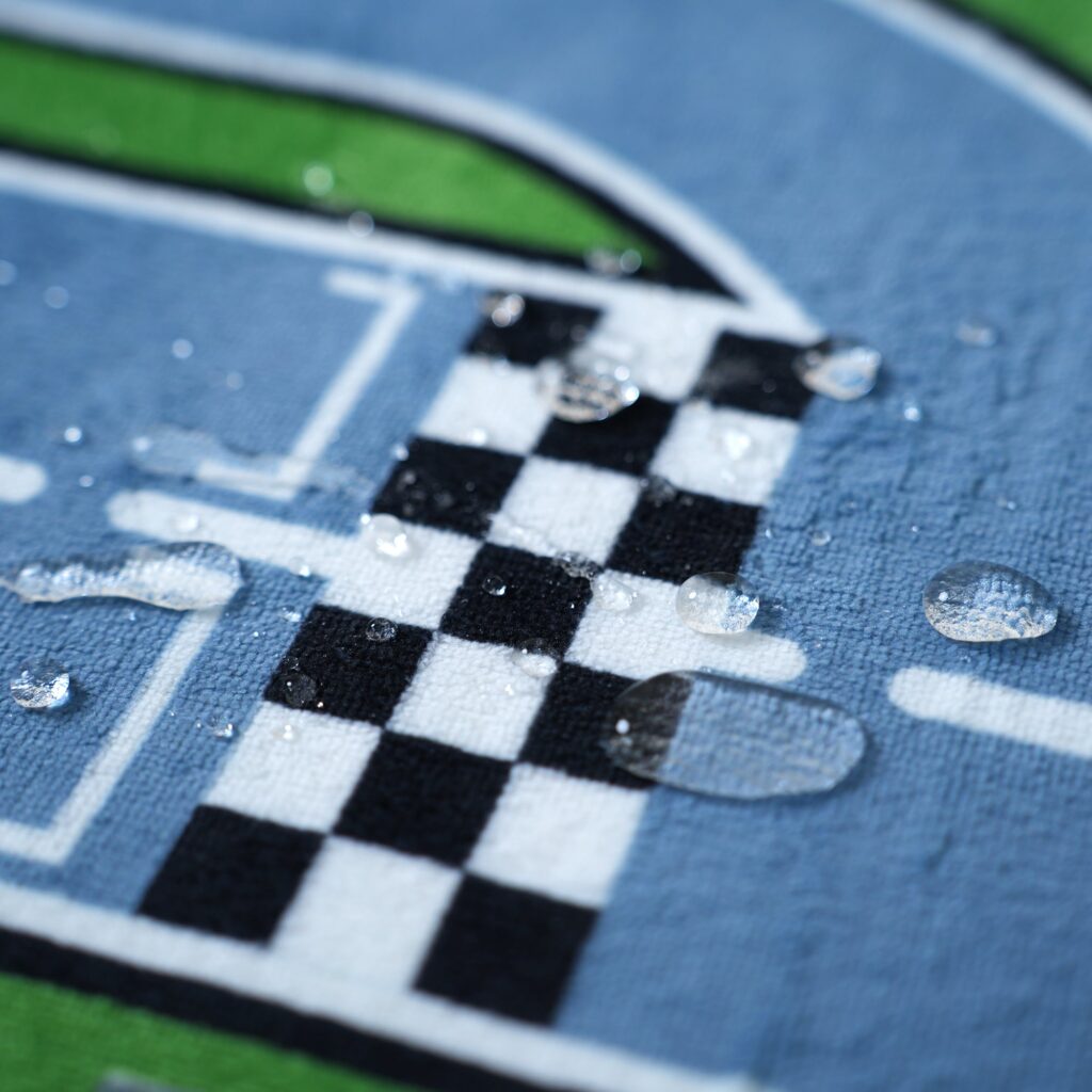 Water droplets beading on the checkered flag print of the PaPaMat Race Track mat