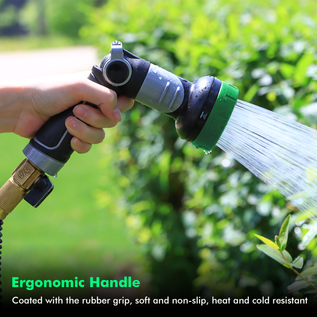 Hand gripping the rubber-coated handle of a Restmo nozzle while it sprays a garden hedge