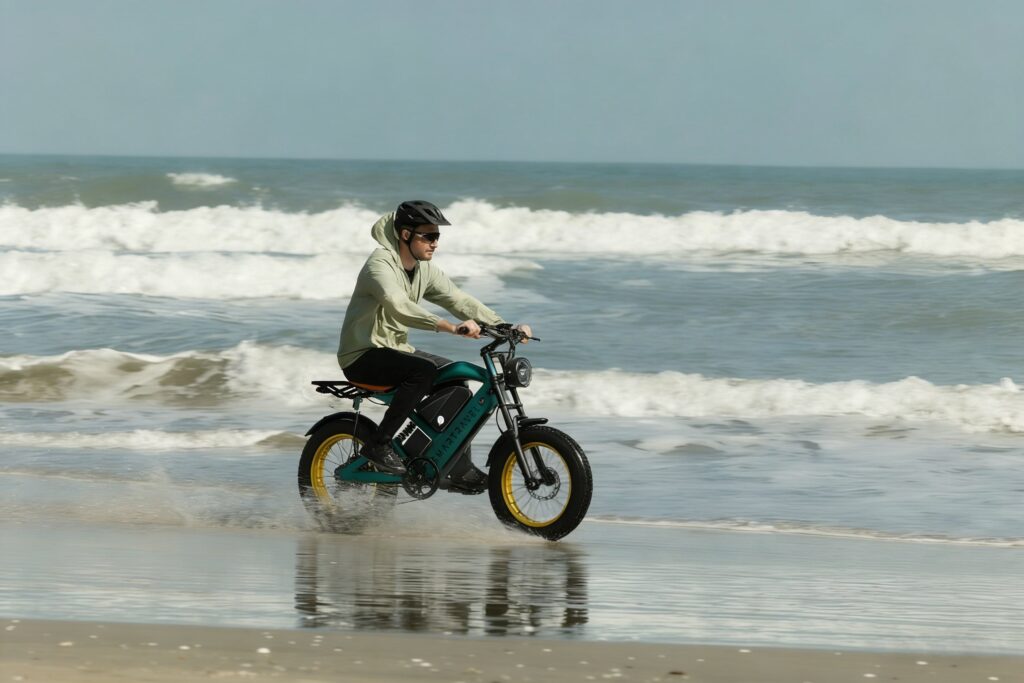 Rider in a light jacket and helmet on a Smartravel e-bike riding through shallow water on a beach