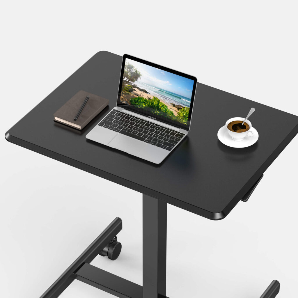 Top-down view of the black desktop of the Sweetcrispy laptop desk holding a laptop, a notebook and a cup of coffee