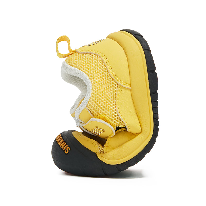 Yellow Taranis toddler shoe standing on its black rubber toe cap with the sole turned to the side