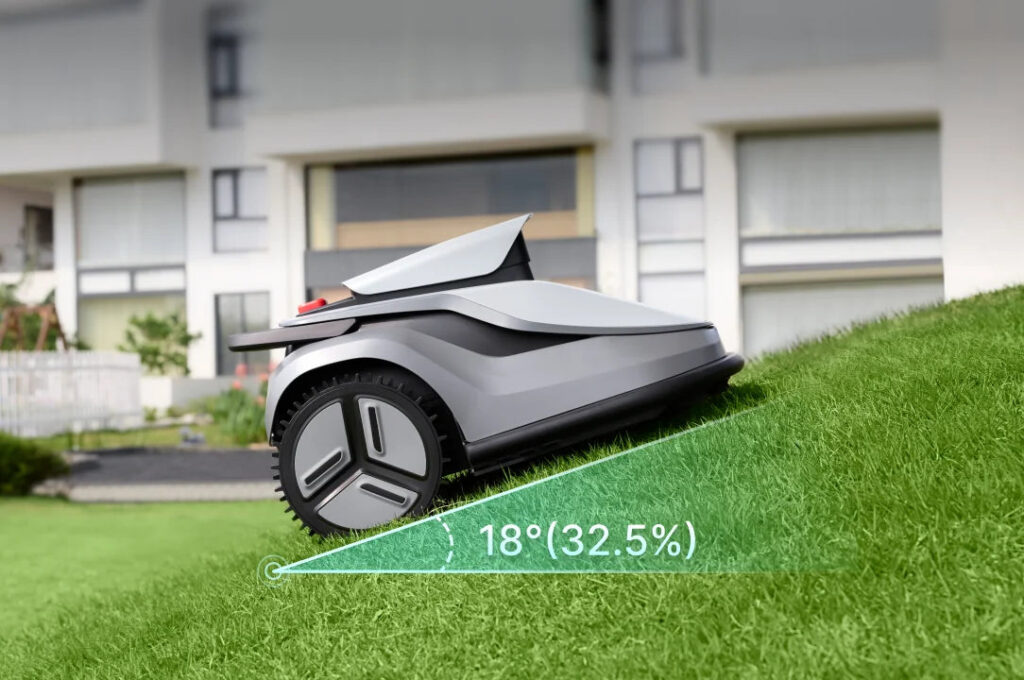 TerraMow V Series robot mower climbing an 18 degree lawn slope in front of a house
